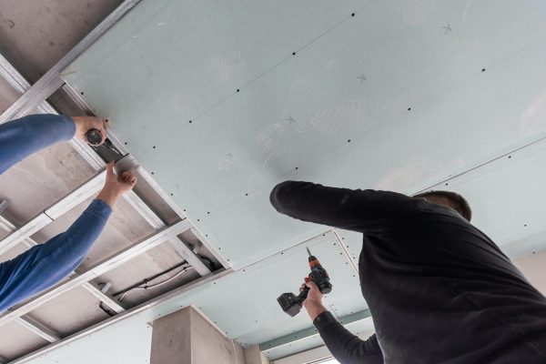 Man assembles profile metal frame for plasterboard ceilings